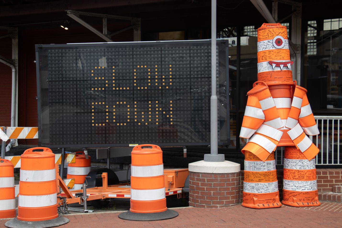 Orange and white safety barrels and an electronic message board reading 