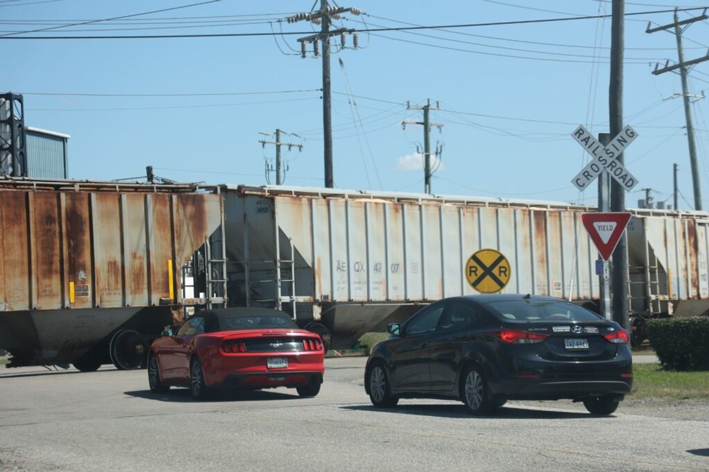Two cars stopped at a railroad crossing as a train passes by
