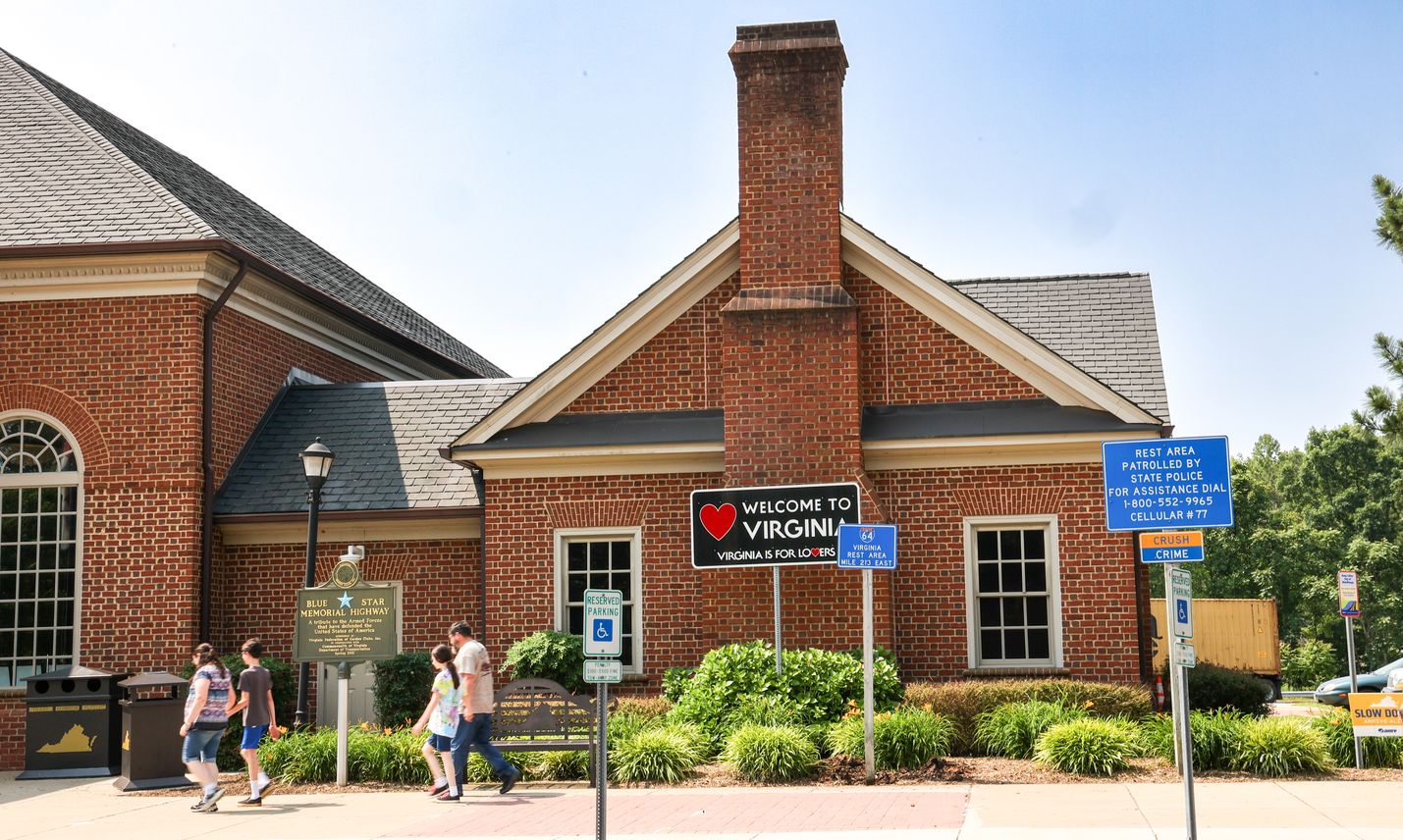 Four people walk toward the entrance of a safety rest area, a brick building that has a 