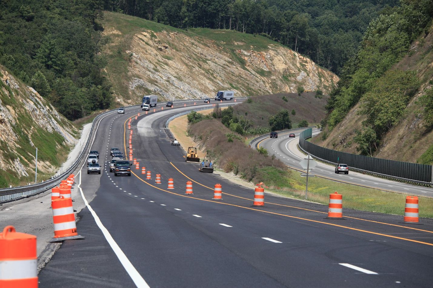 roadway with oncoming cars and orange barrels