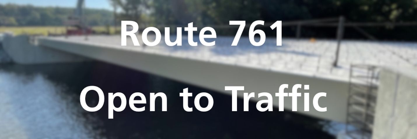Blurred photo of bridge project overlaid with the words, Route 761 open to traffic