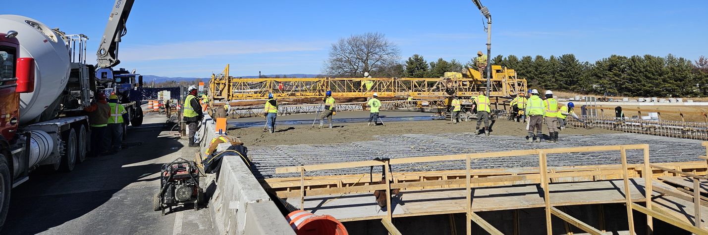 Construction workers and equipment pouring concrete for a new bridge