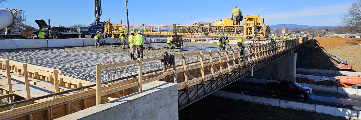 Construction workers and equipment pouring concrete for a new bridge