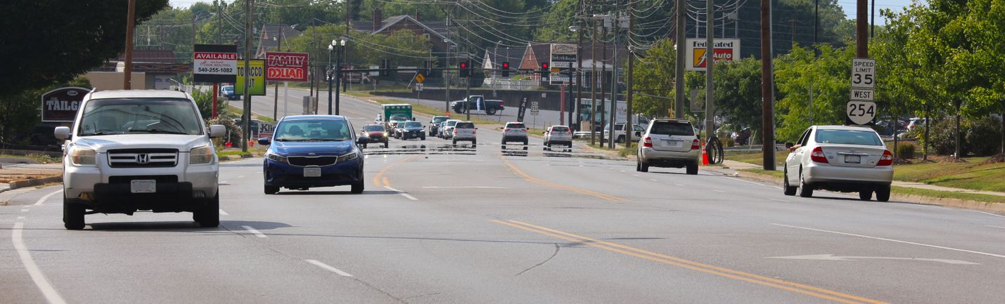 Five-lane roadway in an urban setting with heavy traffic in both directions and a variety of commercial businesses on both sides
