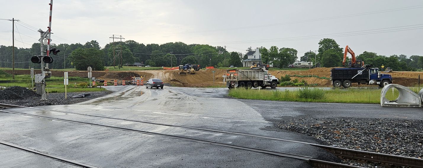 Railroad crossing in the foreground with road closure and construction work in the background