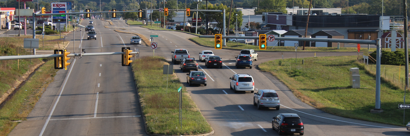 Elevated view of traffic on a moderately busy four-lane roadway, with two signalized intersections visible