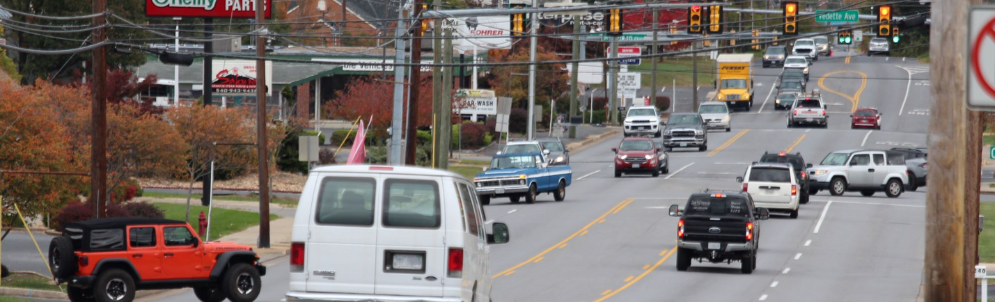 Traffic along a five-lane roadway, with businesses and traffic signals on an overcast day