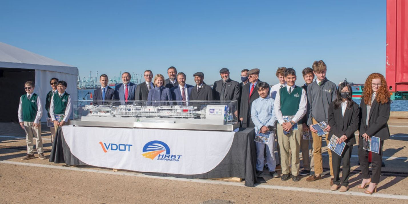 A group of people line up behind a model of the tunnel boring machine