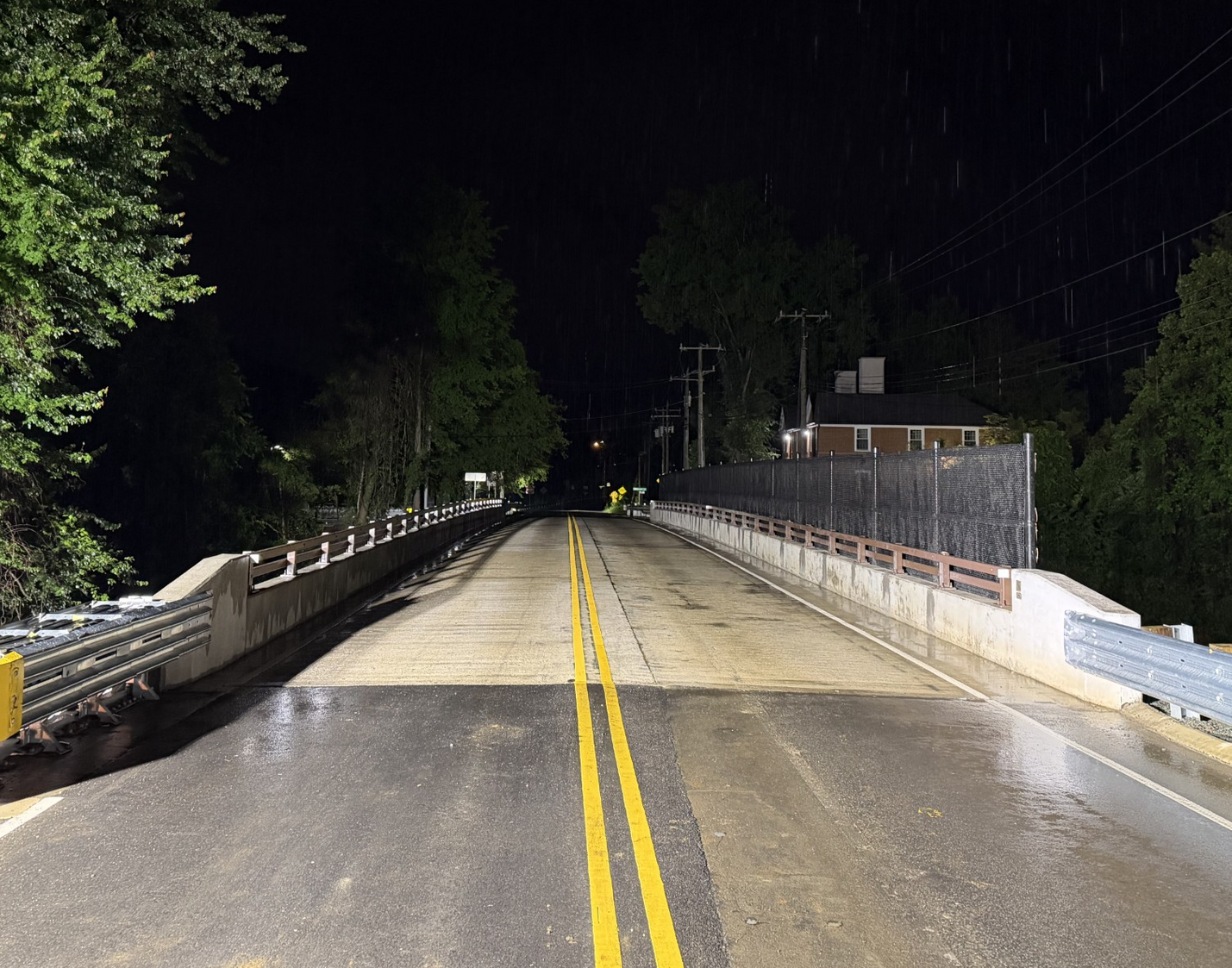 The new Old Ivy Road bridge at night lit by streetlights, with yellow lines reflecting on the road.