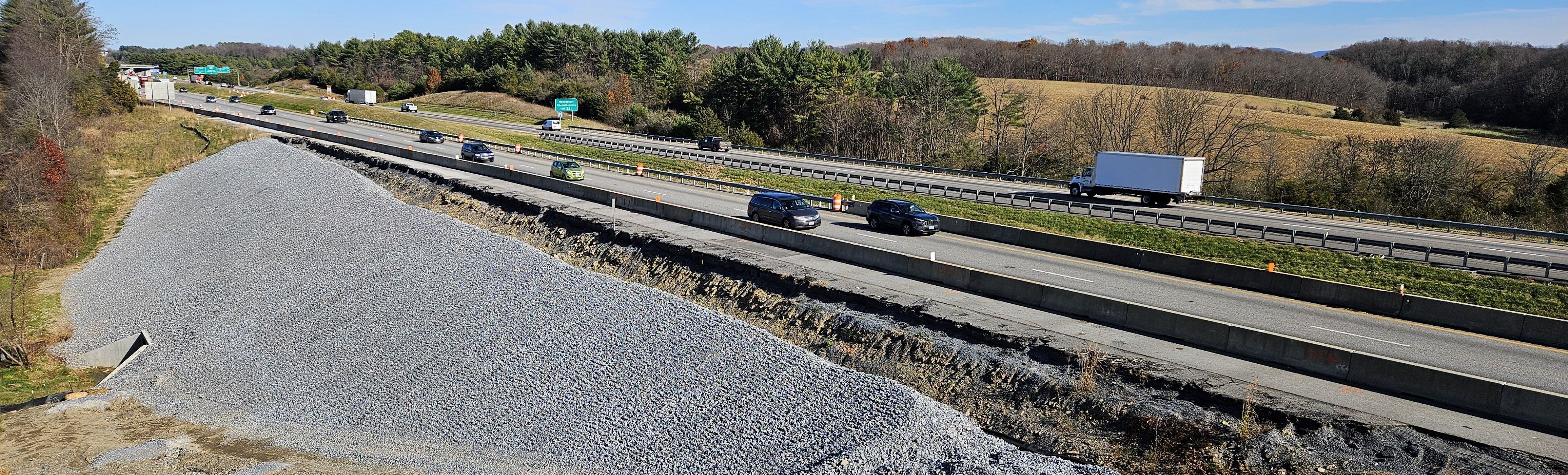 Elevated view of construction work along an interstate highway, showing a large amount of riprap above a culvert