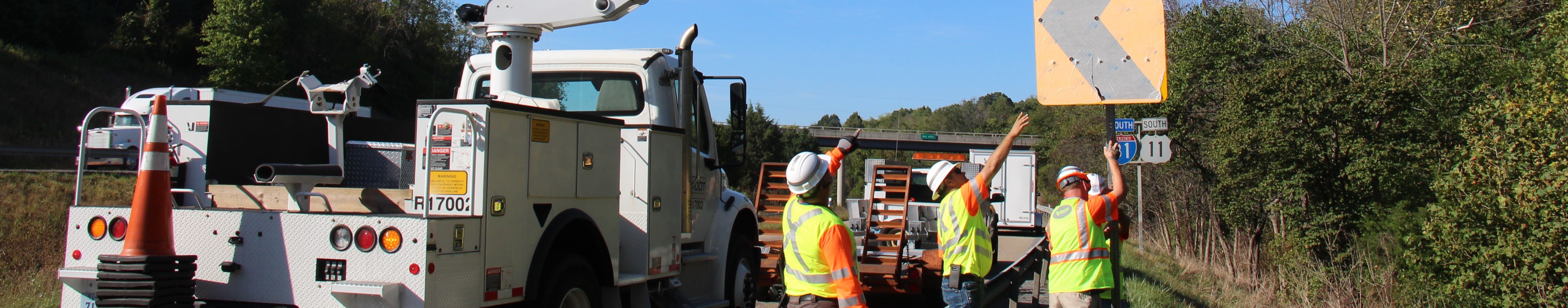 Workers along an interstate highway installing new chevron signs