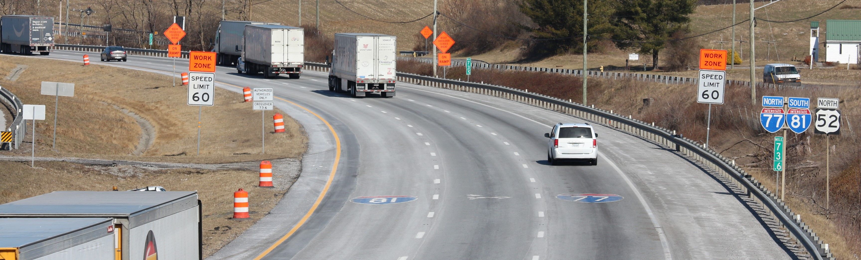 Traffic moving along a curved section of highway. Signs indicate I-81, I-77 and work zone ahead